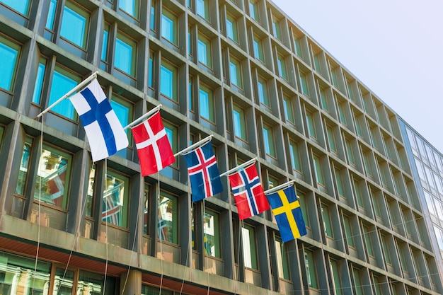 Banderas de los principales países escandinavos en la fachada de un edificio de hotel moderno. De izquierda a derecha: Finlandia, Dinamarca, Islandia, Noruega, Suecia
