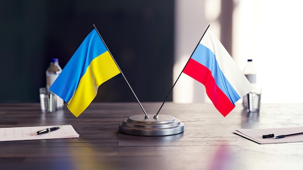 Banderas rusas y ucranianas en una mesa con documentos, bolígrafos, vasos y agua