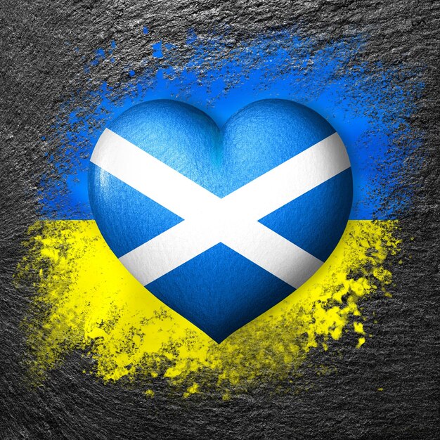 Banderas de Ucrania y Escocia Corazón de bandera en el fondo de la bandera de Ucrania pintada en piedra