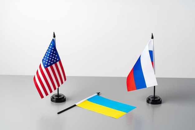 Banderas de ucrania, estados unidos y rusia en mesa gris