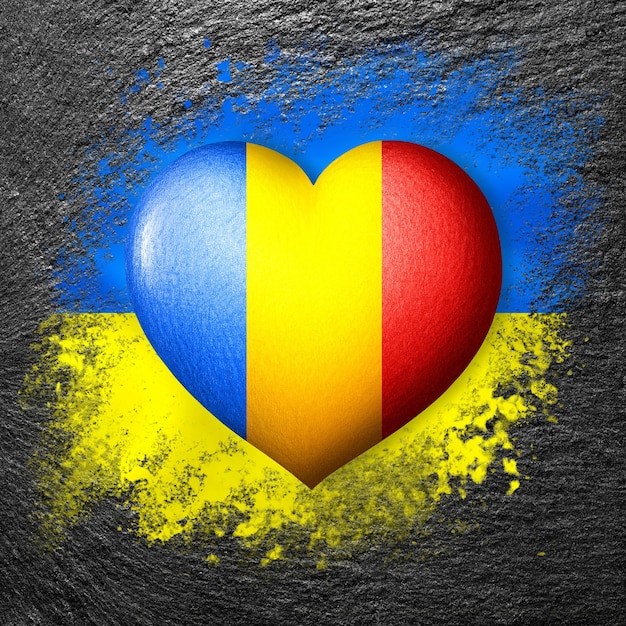 Banderas de Ucrania y Rumania Corazón de bandera en el fondo de la bandera de Ucrania pintada en una piedra