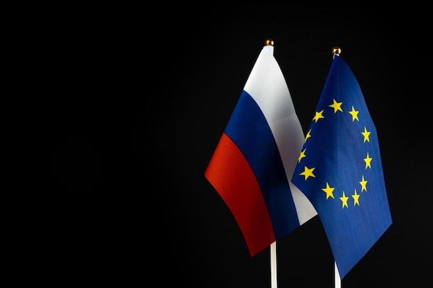 Banderas de la UE y Rusia sobre fondo negro Foto de concepto de política de presión de sanciones Unión Europea vs Rusia Foto de espacio de copia