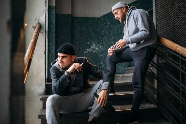 Bandidos esperando a vítima nas escadas e fumando. Ladrão de rua, perigo criminal. Conceito de crime