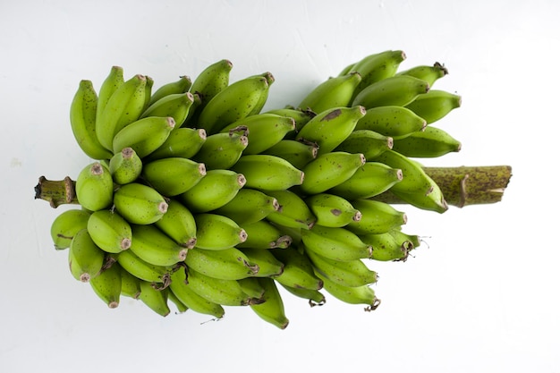 Bando de banana crua ou banana verde colocada sobre uma superfície branca