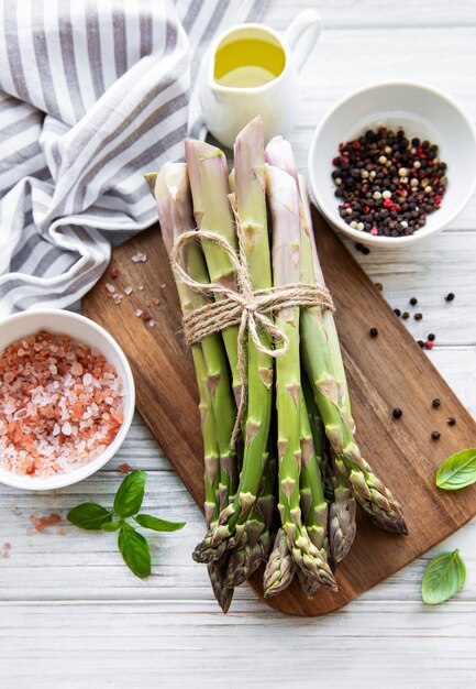 Bando de espargos crus com diferentes especiarias e ingredientes na superfície de madeira