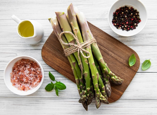 Bando de espargos crus com diferentes especiarias e ingredientes na superfície de madeira