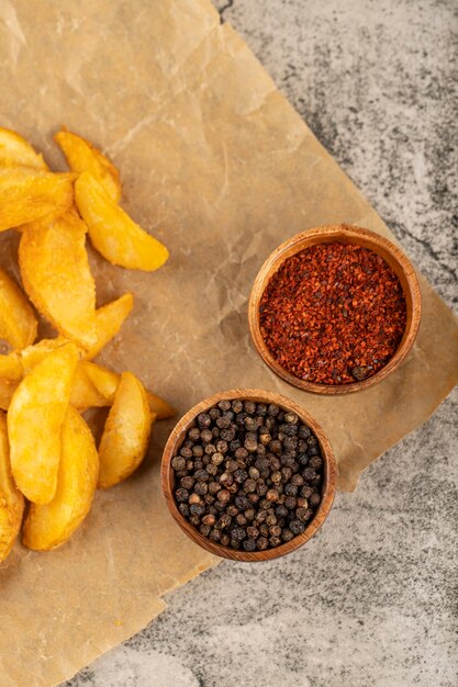 Bando de fatias de batata frita na assadeira com pimenta e pimenta caiena.