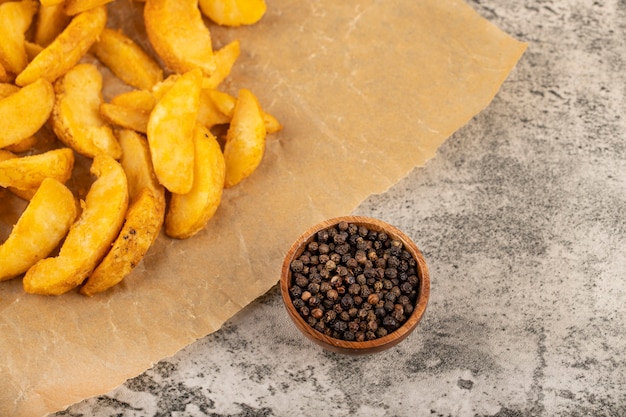 Bando de fatias de batata frita na assadeira com pimenta em grão.