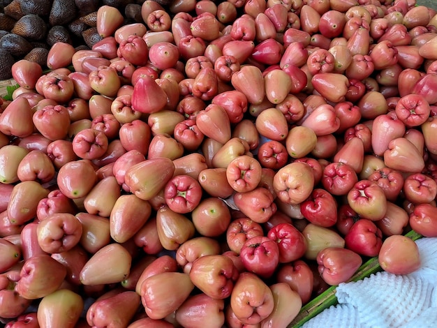 Bando de goiaba de água vermelha doce várias frutas colocadas em mesa de madeira em fundo natural para venda em loja de frutas