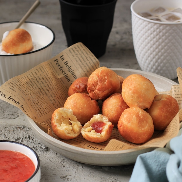 Bandung, Indonesien, 09262020: Indonesisches gebratenes Brot namens Roti/Kue Bantal/Mini Bomboloni mit Erdbeermarmelade oder berühmtem Namen Odading, ausgewählter Fokus.