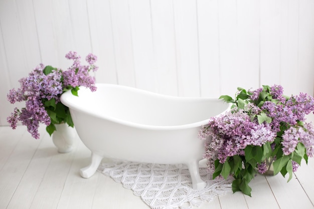 bañera de bebé y un ramo de lilas. flores lilas en el baño. interior del baño