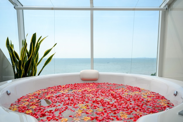 Bañera de lujo con flores de colores en el agua con vista al mar.