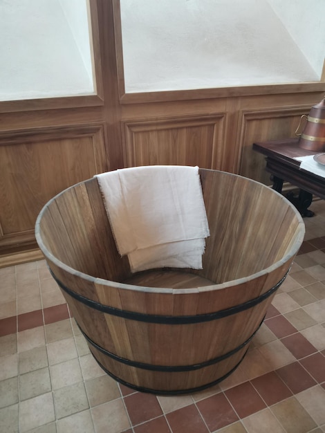 Una bañera de madera en un cuarto de baño con una sábana blanca