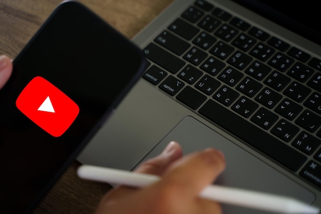 Foto bangkok tailandia 25 de abril de 2022 hombre que usa una computadora portátil para ver el sitio web de youtube con el logotipo de youtube en una pantalla youtube es el sitio en línea más popular del mundo