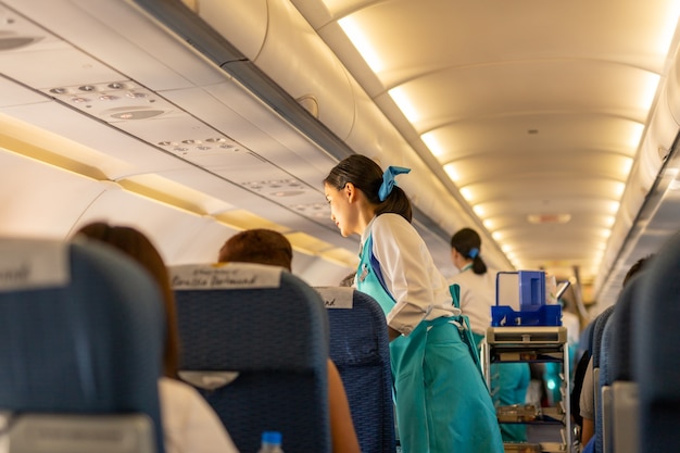 BANGKOK, TAILANDIA - 27 de septiembre de 2018 - El asistente de vuelo de Bangkok Airways sirve bebidas al paso