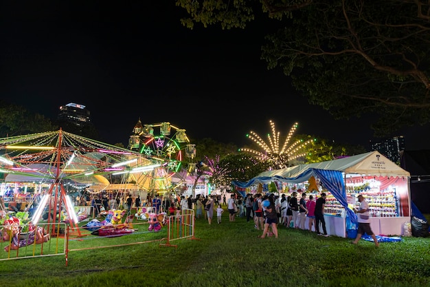 Bangkok Tailandia 8 de diciembre de 2022 Multitudes de personas entran en un parque de atracciones bellamente iluminado durante la Feria de la Cruz Roja que se celebrará a partir del 8 de diciembre de 2022 La imagen está borrosa por el movimiento