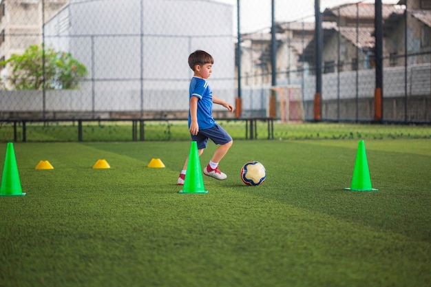 Bangkok - Tailândia NOVEMBRO-10, 2021 Crianças de táticas de bola de futebol controlam a bola em um campo de grama com cone para treinar Tailândia em treinamento de fundo em uma academia de futebol.