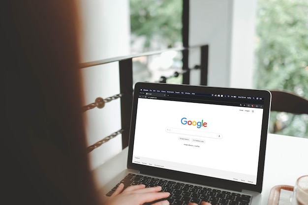 Foto bangkok, tailandia septemper 12022 una mujer está escribiendo en el motor de búsqueda de google desde un portátil google es el motor de búsqueda de internet más grande del mundo