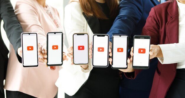 Bangkok/Thailand - 06. August 2021: Menschen halten Smartphones verschiedener Marken und verschiedener Betriebssysteme mit Logos Youtube, dem beliebtesten Videoportal der Welt.