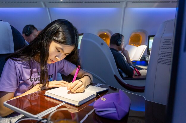 Bangkok, Thailand - 4. April 2015 - ein asiatischer Teenager auf ihrem Notebook schreiben, während er im Flugzeug reist?