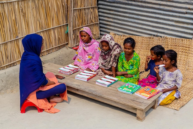 Bangladesch 06. März 2021 Eine Lehrerin sitzt im Freien vor einem Haus im Dorf und unterrichtet einige der armen Kinder in Majherchor Chandpur Chittagong