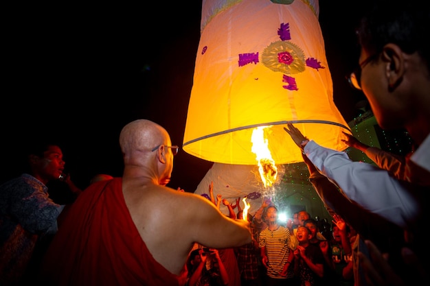 Foto bangladesch 13. oktober 2019 ein buddhistischer mönch versucht mit seinen schülern, eine papierlaterne im buddhistischen tempel ujani para in bandarban, bangladesch, fliegen zu lassen