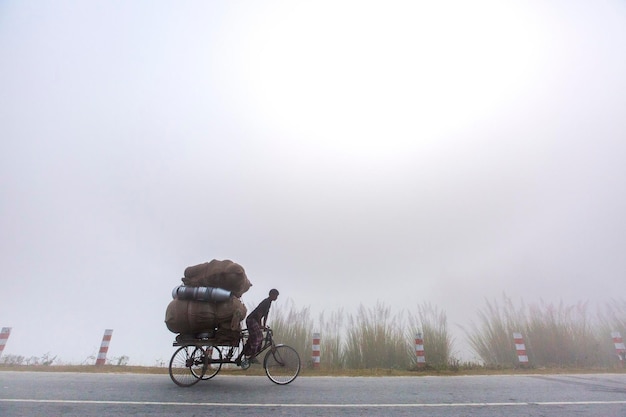 Bangladesh 06 de enero de 2014 En una mañana de niebla de invierno, un trabajador transporta algunas mercancías en una furgoneta en Ranisankail Thakurgaon