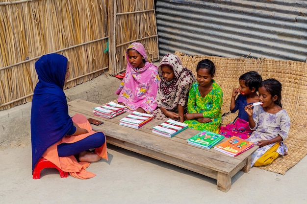 Bangladesh 06 de marzo de 2021 Una maestra está sentada al aire libre frente a una casa en el pueblo enseñando a algunos de los niños pobres en Majherchor Chandpur Chittagong