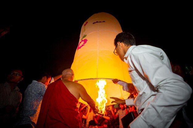 Foto bangladesh 13 de octubre de 2019 un monje budista con sus discípulos tratando de volar una linterna de papel en el templo budista ujani para en bandarban bangladesh