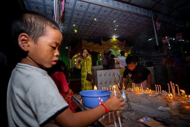 Foto bangladesh 13 de octubre de 2019 un niño adorador está encendiendo velas en el templo budista ujani para en bandarban bangladesh