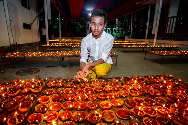 Foto bangladesh el 13 de octubre de 2019 un niño tribal budista está encendiendo velas en el templo budista ujani para en bandarban bangladesh