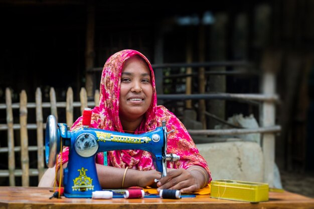 Bangladesh 19 de mayo de 2019 Una aldeana de mediana edad se sienta en el patio trasero cosiendo para su familia