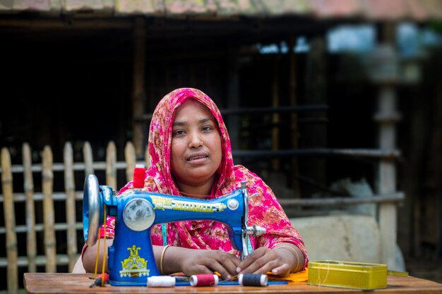 Bangladesh 19 de mayo de 2019 Una aldeana de mediana edad se sienta en el patio trasero cosiendo para su familia