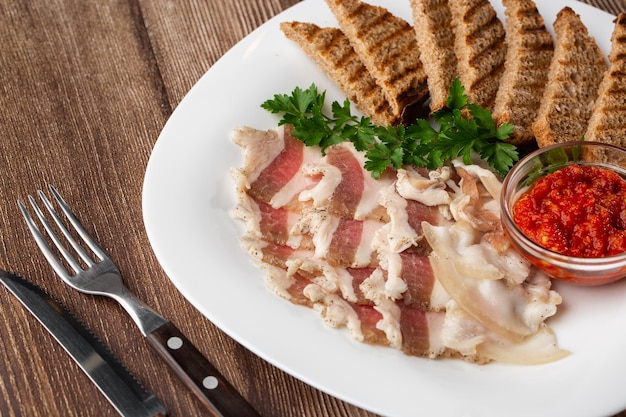 Banha de porco crua picada com carne uma cabeça de alho e pão de centeio em um fundo de madeira para espaço de cópia Um grande pedaço de banha ucraniana gordura fresca comida tradicional