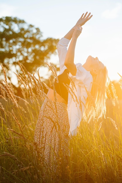 Banhando-se ao sol jovem loira em pé no meio do campo de trigo