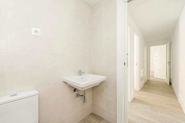 Banheiro com piso de madeira de pia de porcelana branca em um longo corredor com acesso a outros cômodos
