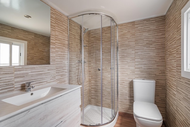 Banheiro simples com móveis de madeira de banheiro branco de cabine de chuveiro e azulejos bege interior de refurbus