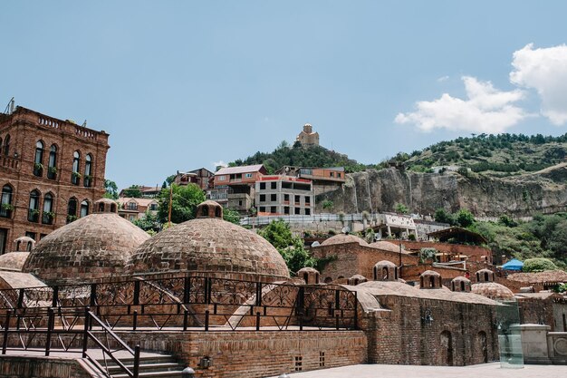 Foto banhos de enxofre na cidade velha em casas georgianas de tbilisi no contexto da fortaleza narikala city paisagem geórgia