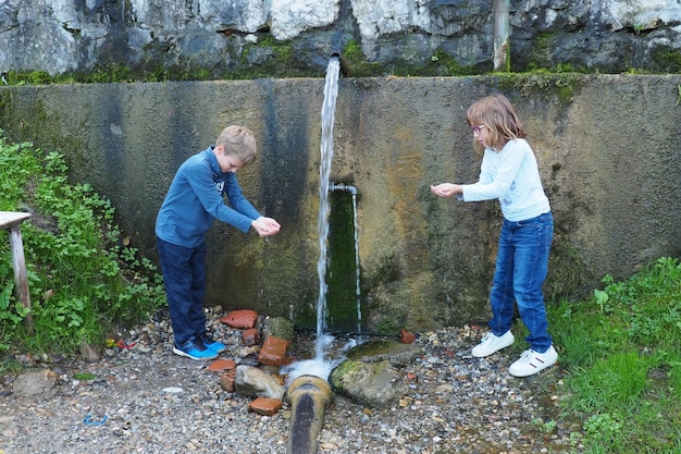 Banja Koviljaca Loznica Sérvia Parque e floresta do Monte Guchevo Fonte de água mineral sulfúrica e ferruginosa Ilidja Chesma Cesma Um jato de água jorra de uma torneira em uma parede de concreto Menino e menina