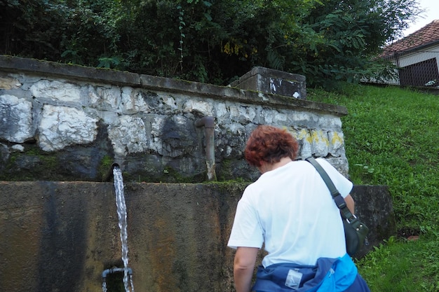 Banja Koviljaca Loznica Sérvia Parque e floresta do Monte Guchevo Fonte de água mineral sulfúrica e ferruginosa Ilidja Chesma Cesma Um jato de água jorra de uma torneira em uma parede de concreto Uma mulher