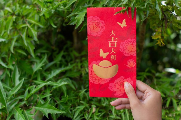 Banjarnegara Januar 2023 Red Angpao in einer Hand gehalten mit natürlichem grünem, unscharfem Hintergrund Chinesisches Neujahr