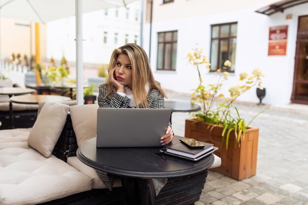 Bankangestellte der erwachsenen Frau, die online auf Laptop im Stadtcafé arbeitet