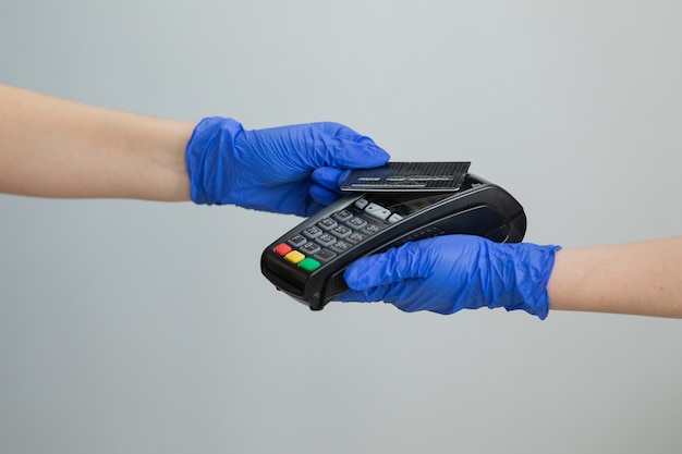 Bankdienstleistungen für elektronisches Geld. Finanzieller Erfolg und Sicherheit. Kreditkartenautomat für Geldtransaktion. Frau Hand in Handschuhen mit Kreditkarte durch pos Terminal wischen und PIN-Code eingeben.