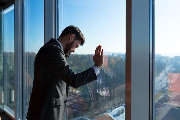 Bankrotter Geschäftsmann-Chef frustriert, der aus dem Fenster schaut Mann im Business-Anzug deprimiert und frustriert im modernen Büro