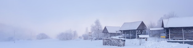 Banner 41 com uma paisagem montanhosa de inverno e uma vila coberta de neve com galpões e toras de lenha