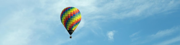 Banner 4x1 com um balão multicolorido voador no contexto de um céu azul com nuvens