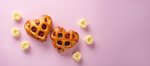 Banner amplo do Dia dos Namorados Pães de coração Twain com geléia de bagas e crosta de treliça em um fundo rosa claro com rosas brancas de chocolate Espaço de cópia plana leiga para vista superior do texto