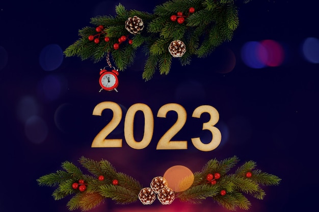 Banner de Año Nuevo con números de madera 2023 ramas de árboles de Navidad piñas y despertador rojo