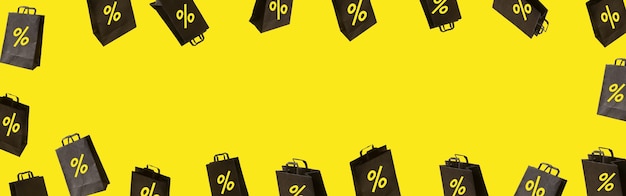 Foto banner con bolsas de la compra de venta negras están volando sobre fondo amarillo. concepto de idea creativa de viernes negro