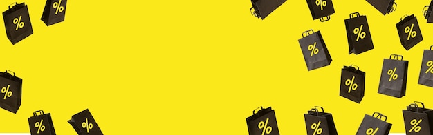 Foto banner con bolsas de la compra de venta negras están volando sobre fondo amarillo. concepto de idea creativa de viernes negro